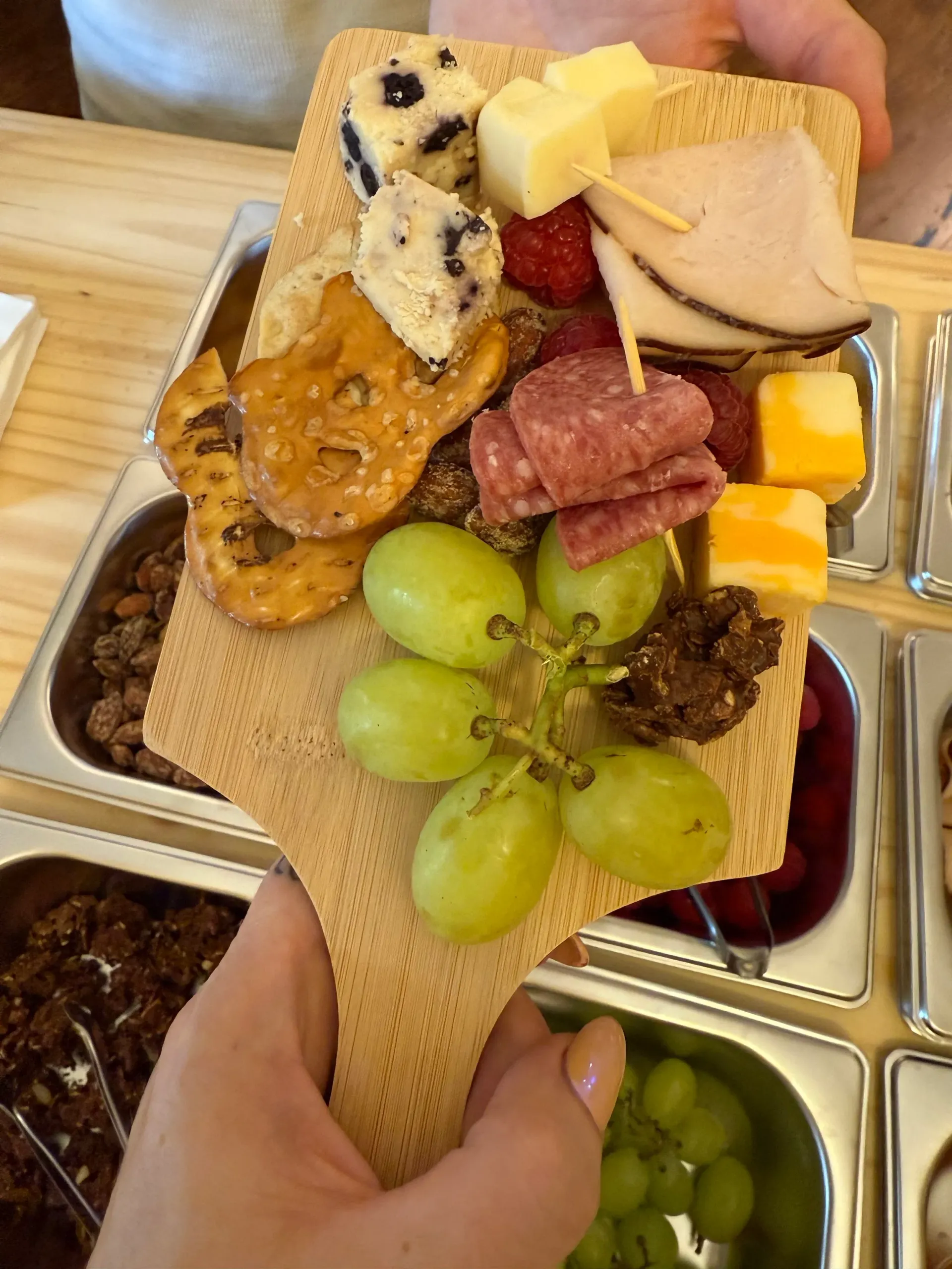 A mini grazing board filled with cheeses, fruit, meats, and sweets